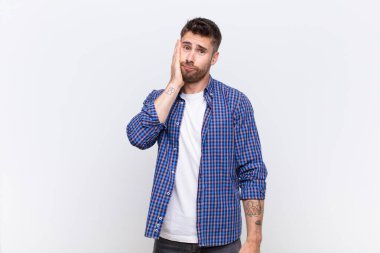 Genç adam şok olmuş ve şaşkınlık içinde. Düz renkli duvara karşı ağzı sonuna kadar açık bir şekilde inanmamazlıktan geliyor.