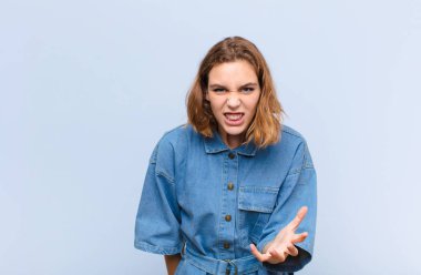 Genç sarışın kadın kızgın, sinirli ve hayal kırıklığına uğramış görünüyor. Duvara karşı ne ya da neyin var senin? 