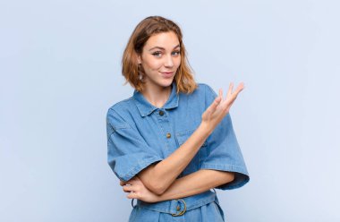 Genç sarışın kadın, kafası karışık ve cahil, şüpheli bir açıklamayı merak ediyor ya da düz renkli duvara karşı düşünce