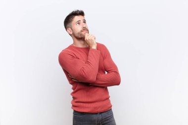 Genç Handome düşünceli, meraklı ya da hayalperest, hayal kuran, düz renkli duvara karşı boşluğu kopyalamak isteyen bir adam.