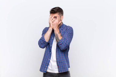 Genç handosme adam korkmuş ya da utanmış hissediyor. Gözleri yarı kapalı, düz renkli duvara bakıyor ya da dikizliyor.