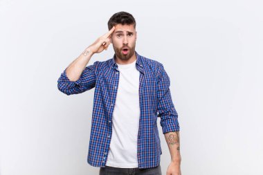 Genç adam şaşırmış, ağzı açık, şok olmuş, düz renk duvarına karşı yeni bir düşünce, fikir ya da konsept keşfediyor.