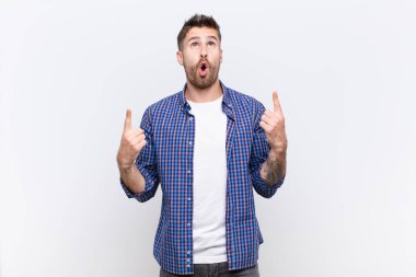 Genç Handome hayranlık duyuyor ve ağzı açık. Düz duvara karşı şaşkın ve şaşkın bir bakışla yukarıya bakıyor.