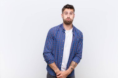 Şapşal, çılgın, şaşırmış yüz ifadesiyle genç handome adam, şişmiş yanaklar, doldurulmuş hissetmek, şişman ve düz renkli duvarlara karşı yemek dolu.