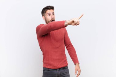 Genç adam şok olmuş ve şaşırmış hissediyor, şaşırmış ve şaşkınlıkla yukarı bakıyor, şaşırmış, ağzı açık bir şekilde düz duvara bakıyor.