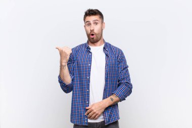 Genç Handome, inançsızlıktan şaşkın şaşkın bakıyor, yan taraftaki objeyi işaret ediyor ve diyor ki vay be, düz renkli duvara karşı inanılmaz