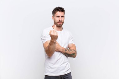 Genç Handome sinirli, sinirli, asi ve agresif hissediyor, orta parmağını sallıyor, düz renkli duvara karşı savaşıyor.