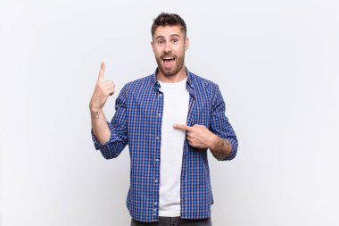 Genç Handosme gururlu ve şaşırmış hissediyor, kendine güvenen, düz renkli duvara karşı bir numara gibi hisseden