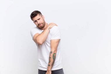 Genç adam endişeli, hasta, hasta ve mutsuz hissediyor. Acı çeken bir mide ağrısı ya da düz bir duvarda grip geçiriyor.