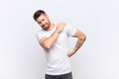 Genç adam yorgun, stresli, endişeli, hayal kırıklığına uğramış ve depresif hissediyor. Sırtı ya da boynu düz duvarda ağrıyor.