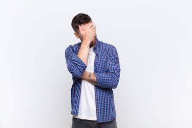 Genç adam stresli, utanmış ya da üzgün görünüyordu. Başı ağrıyordu. Yüzü düz duvarla kaplıydı.