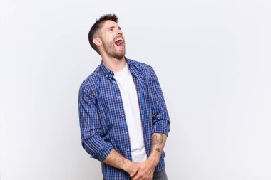 Genç adam öfkeyle bağırıyor, agresif bir şekilde bağırıyor, stresli ve sinirli görünüyor.