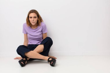 Aptal, çılgın, şaşırmış bir ifadeyle genç sarışın kadın, şişmiş yanaklar, doldurulmuş, şişman ve düz renkli duvarda yemek dolu.