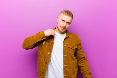 Genç sarışın adam kibirli, başarılı, pozitif ve gururlu görünüyor, mor arka planda kendini gösteriyor.