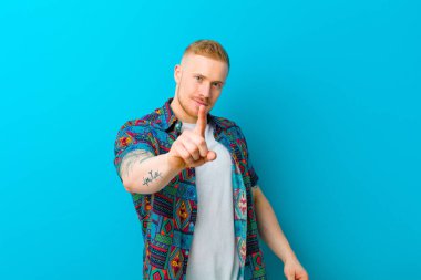 Baskı tişörtü giyen genç sarışın gururla gülümsüyor ve bir numaralı pozu başarıyla veriyor, kendini lider gibi hissediyor.