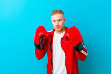 Mavi arka planda spor kıyafetleri giyen genç sarışın adam. fitness konsepti