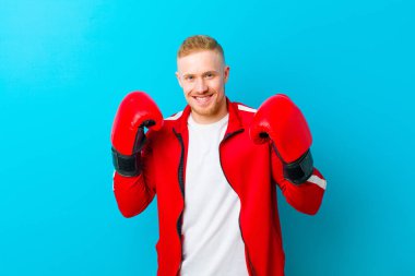 Mavi arka planda spor kıyafetleri giyen genç sarışın adam. fitness konsepti