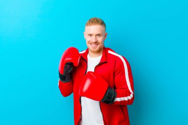 Mavi arka planda spor kıyafetleri giyen genç sarışın adam. fitness konsepti