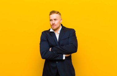 Genç sarışın iş adamı şüpheye düşüyor ya da düşünüyor, dudağını ısırıyor ve kendini güvensiz ve gergin hissediyor, kenarda yer arıyor.