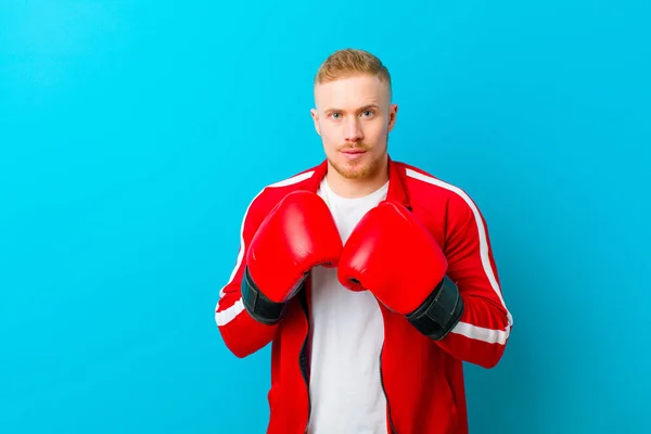 young blonde man wearing sports clothes  against blue background. fitness concept