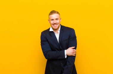 Genç sarışın işadamı utangaç ve neşeli bir şekilde gülüyor, arkadaş canlısı ve olumlu ama güvensiz bir tavırla