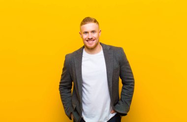 Genç, sarışın iş adamı neşeli, neşeli, mutlu, kendinden emin ve rahat bir ifadeyle gülümsüyor.