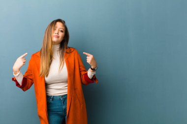 Kötü tavırlı genç ve güzel bir kadın gururlu ve agresif görünüyor, yukarıyı işaret ediyor ya da elleriyle alay işareti yapıyor.