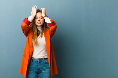 Genç ve güzel bir kadın stresli ve endişeli, depresif ve hayal kırıklığına uğramış hissediyor, iki elini de başa kaldırıyor.