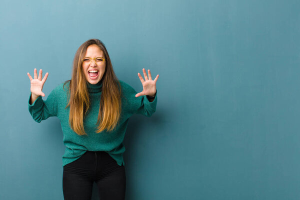 young pretty woman screaming in panic or anger, shocked, terrified or furious, with hands next to head