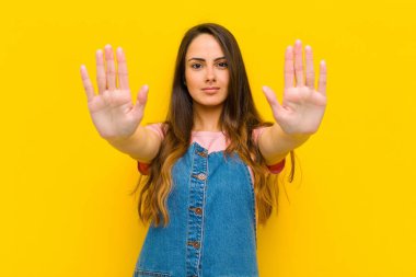 Genç ve güzel bir kadın ciddi, mutsuz, kızgın ve hoşnutsuz görünüyor. Ya da her iki avucunun içinde de dur diyor.