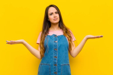 Şaşkın, kafası karışmış ve stresli görünen genç bir kadın. Farklı seçenekler arasında merak ediyor, kararsız.