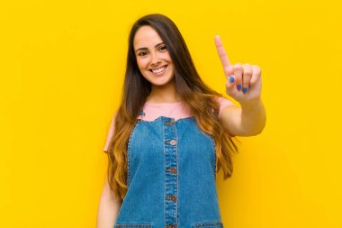 Genç, güzel bir kadın gülümsüyor ve arkadaş canlısı görünüyor. İki ya da iki numarayı gösteriyor. Elleri önde, geri sayıyor.