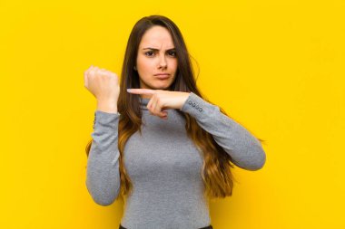 Genç ve güzel bir kadın sabırsız ve kızgın görünüyor, saati gösteriyor, dakiklik istiyor, işe ya da iş konseptine uymak istiyor.