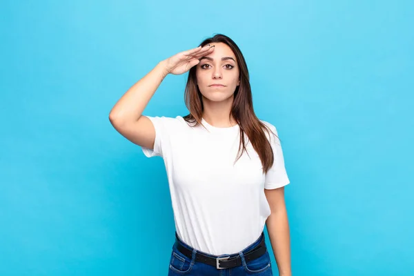 青い壁に敬意を示す名誉と愛国心の行為で軍の敬礼でカメラを迎える若い女性 — ストック写真