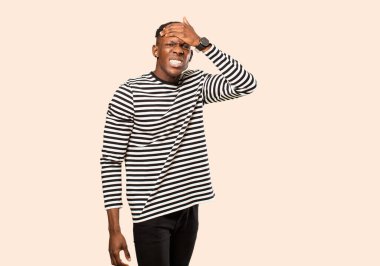 Genç Afrikalı Amerikalı siyahi adam unutulmuş bir mühlet yüzünden panikliyor, stresli hissediyor, bej rengi duvara karşı bir karmaşayı veya hatayı örtbas etmek zorunda kalıyor.