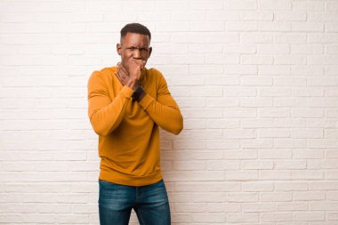 Genç Afrikalı Amerikalı siyahi adam boğazı ağrıyan ve grip belirtileri gösteren, ağzı tuğla duvarla kaplı öksüren