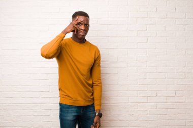 Genç Afro-Amerikan siyahi adam şok olmuş, korkmuş ya da korkmuş görünüyor. Yüzü elle örtülmüş ve parmakların arasından duvara bakıyor.