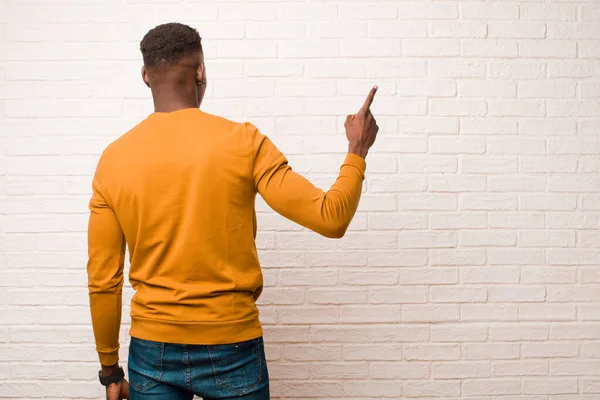アフリカ系アメリカ人の黒人青年が立ち上がってコピースペースを指差し込みレンガの壁に向かって — ストック写真