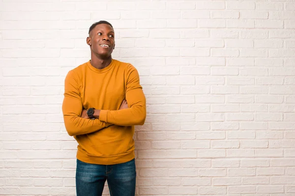 若いアフリカ系アメリカ人黒人の男は レンガの壁に対して腕を組んでスペースをコピーすることを考えているかどうか疑問に思い 誇りと希望を感じています — ストック写真