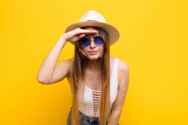 Genç, güzel bir kadın şaşkınlık ve şaşkınlık içinde bakıyor. Alnı açık, uzaklara bakıyor, izliyor ya da arıyor.