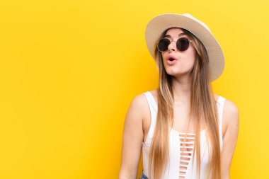 Genç, güzel bir kadın şaşkın, mutlu, şaşkın ve şaşırmış hissediyor, ağzı açık bir şekilde yana bakıyor.