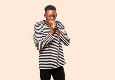 Genç Afrikalı Amerikalı siyahi adam boğazı ağrıdığı ve grip belirtileri gösterdiği için öksürüyor.