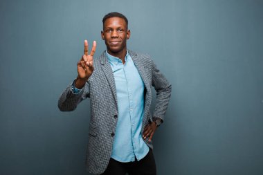 Genç Afro-Amerikan siyahi adam gülümsüyor ve arkadaş canlısı görünüyor, üç ya da üçüncüyü eli önde gösteriyor, geri sayıyor.