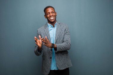 Genç Afrikalı Amerikalı siyah adam mutlu ve başarılı hissediyor, gülümsüyor ve alkışlıyor, alkışlarla tebrik ediyor.