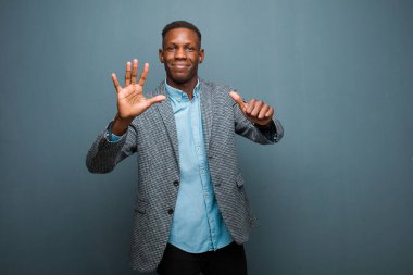 Genç Afro-Amerikan siyahi adam gülümsüyor ve arkadaş canlısı görünüyor, 6 ya da 6 numarayı gösteriyor, elleri önde, geriye doğru sayıyor.