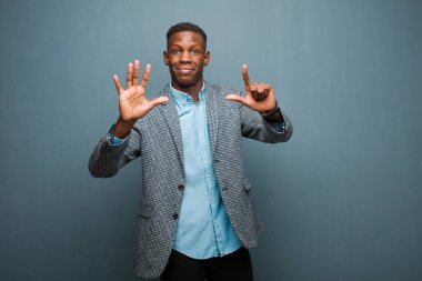 Genç Afro-Amerikan siyahi adam gülümsüyor ve dost canlısı görünüyor. Elleri önde, geriye doğru sayıyor.