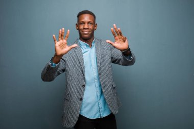 Genç Afro-Amerikan siyahi adam gülümsüyor ve dost canlısı görünüyor. Dokuzuncu ya da dokuzuncu eli önde, geriye doğru sayıyor.