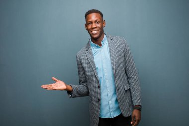 Genç Afro-Amerikan siyahi adam neşeyle gülümsüyor, mutlu hissediyor ve fotokopi uzayında bir konsept gösteriyor.