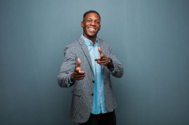 Genç Afrikalı Amerikalı siyahi adam mutlu, sakin, tatmin olmuş, rahat ve başarılı hissediyor, kameraya bakıyor, seni grunge duvarına karşı seçiyor.