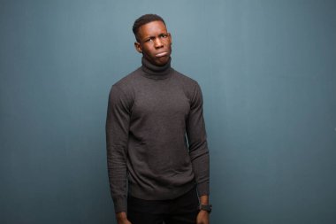 Genç Afro-Amerikan siyahi adam üzgün ve mızmızlanıyor. Mutsuz bir bakışla, olumsuz ve hayal kırıklığına uğramış bir tavırla grunge duvarına karşı ağlıyor.